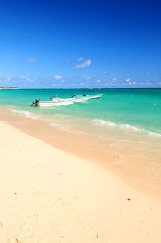 Fishing boats in Caribbean sea anchored near sandy beach