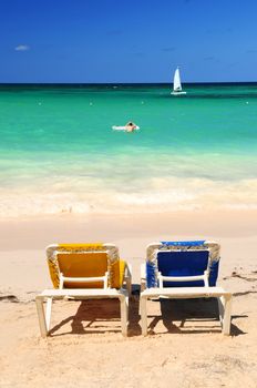 Two vacation chairs on sandy tropical beach of Caribbean island