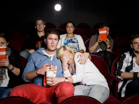 Young scared couple at the movie theater