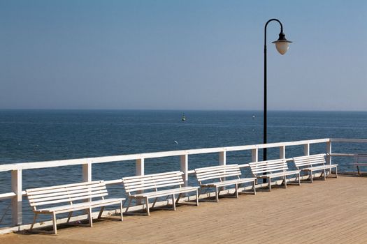 Wooden pier with white benches
