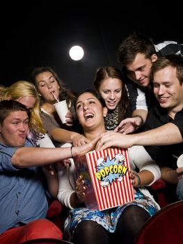 Group of young spectators eating popcorn at the movie theater