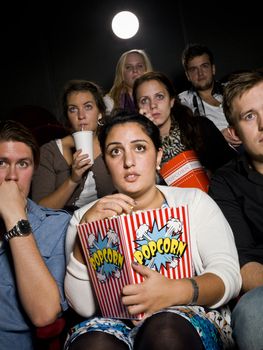 Afraid young woman at the movie theater with bag of popcorn