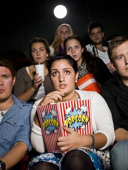 Afraid young woman at the movie theater with bag of popcorn