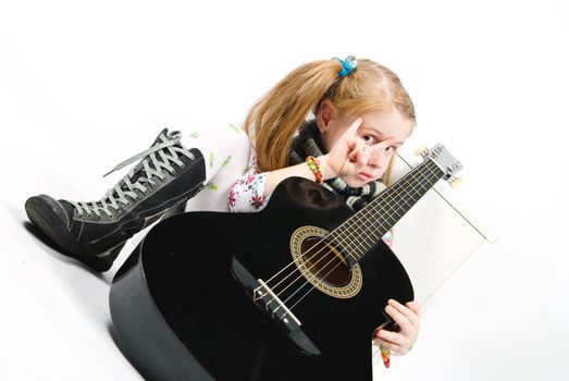 studio shot of pretty little girl playing black acoustic guitar