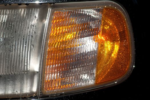 Headlight of an SUV in the rain by night with water