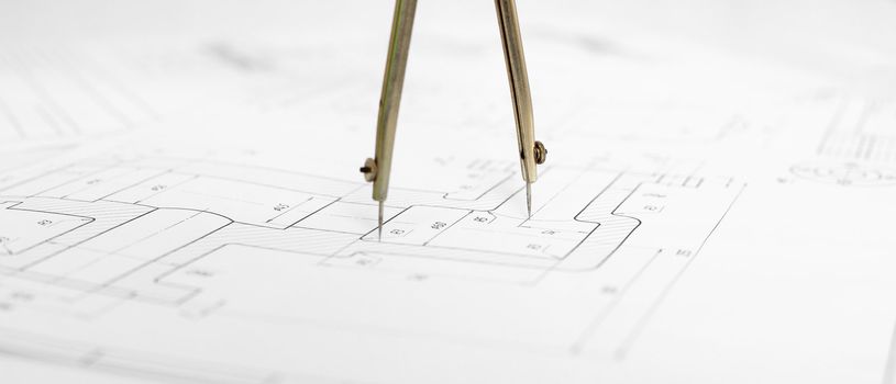 Metal compasses against the engineering drawing close up