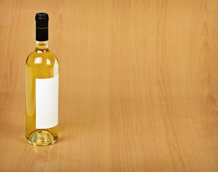 A bottle of white wine stands on a wooden table