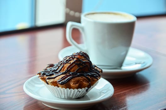 Chocolate muffins with and coffee cup on orange table