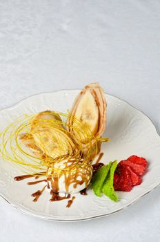 Dessert of pancake with banana, ice-cream, caramel, strawberry and mint