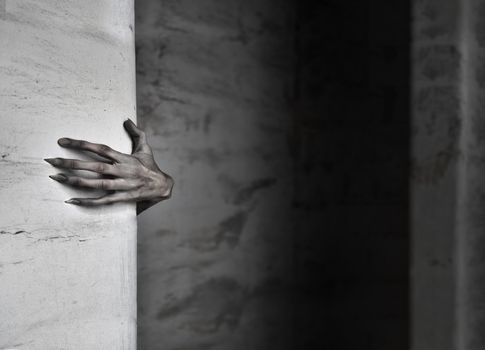 A spooky female hand protruding from behind a wall