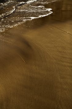 The ebb of the waves creating beautiful patterns on a sand bank