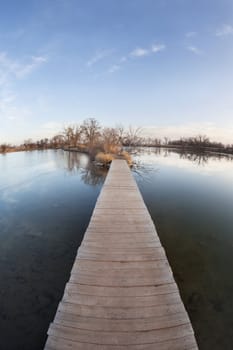 pathway, journey or goal concept - boardwalk and trail across lake and swamp, wide angle fisheye lens perspective, late fall scenery with ice cover