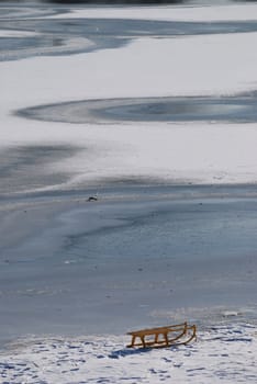Small frozen river with sledge on snow and ice