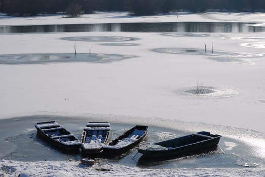 Winter landscape. Small frozen river and boats  on ice