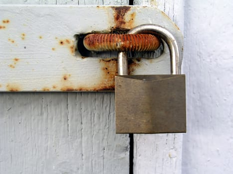 Old rusty padlock on white wood door closeup
