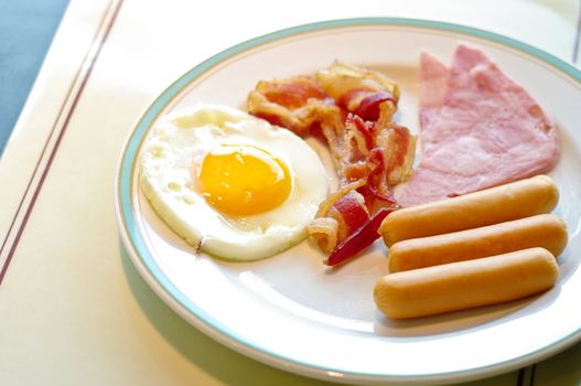 Breakfast, fried egg and sausage in white dish