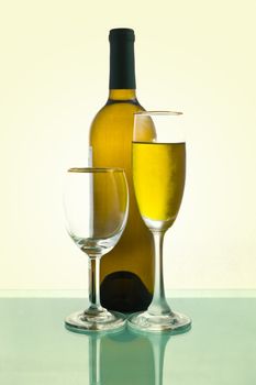 Bottles and glasses of wine on green background