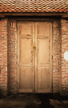 Old brown wooden door against an old wall in Thailand