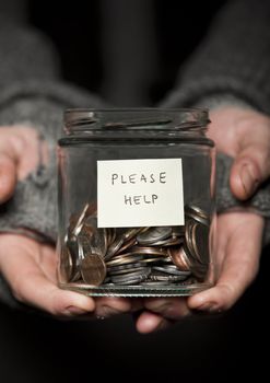 Close up of a Beggars hands and jar of coins