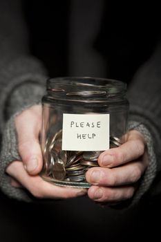 Close up of a Beggars hands and jar of coins