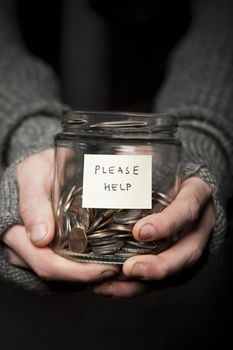 Close up of a Beggars hands and jar of coins