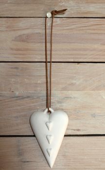 four hearts on cermaic pendant against a wooden background