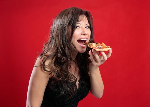 A beautiful happy woman eating a slice of tasty italian pizza. 