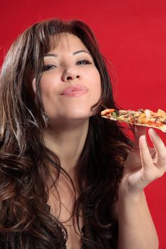 A woman with dark brown hair is enjoying delicious slice of italian pizza.