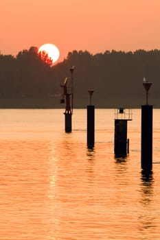 Orange sunset at the riverside - stakes with markings for ships