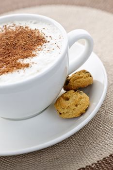 Cappuccino or latte coffee in cup with frothed milk and cookies