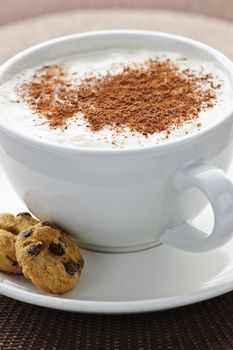 Cappuccino or latte coffee in cup with frothed milk and cookies