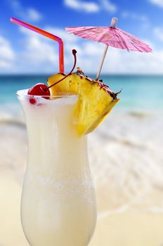 Pina colada drink in cocktail glass with tropical beach in background