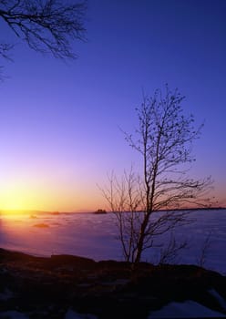 Beautiful winter landscape of snowy lake at sunset