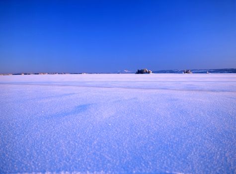Landscape image of a snowy meadow and blue sky