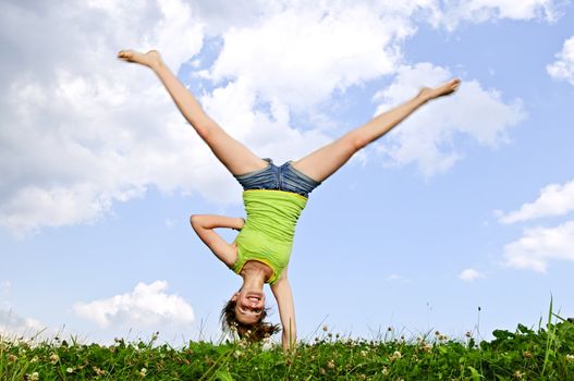 Young teenage girl doing cartwheel in a summer meadow