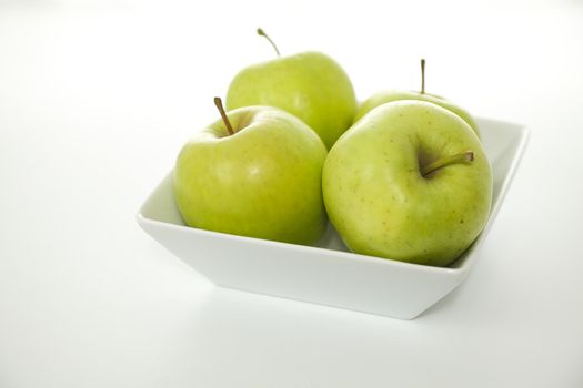 Green Crispin Mutsu Apples in a White Bowl on a White Background in Minimalist Style