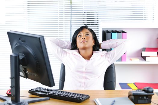 Young black business woman resting at desk in office