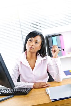 Young black business woman thinking at desk in office