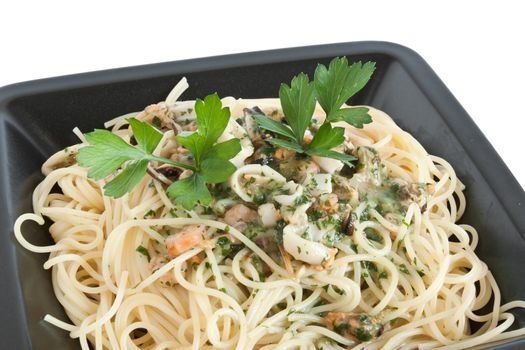 spaghetti with shrimps, squids, mussels and parsley isolated on white
