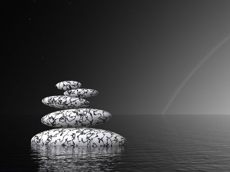 Balanced black and white stones alone in the ocean by night with a little rainbow