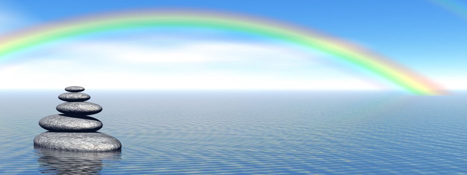 Balanced grey stones in the deep blue ocean with a beautiful rainbow
