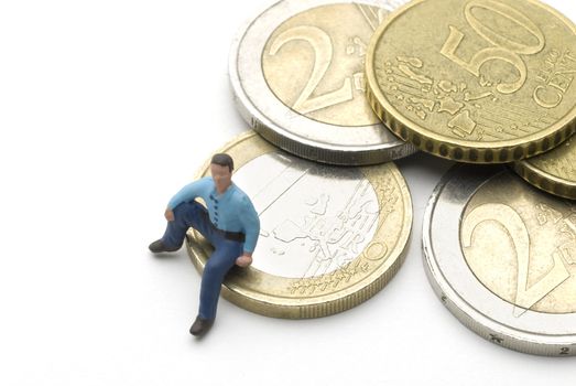 Man (puppet) sitting on Euro coins. A saving metaphor