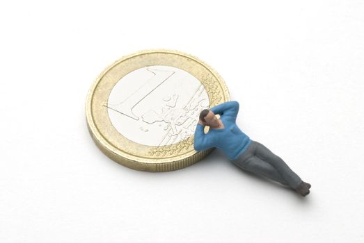 Man (puppet) sleeping on a Euro coin currency. 
A saving metaphor.
Included a clipping path