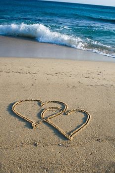 Two ensambled hearts drawn in the sand of a beach