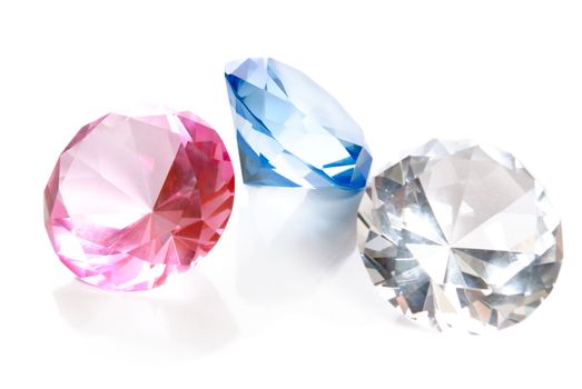 Fake colored gems in the shape of large diamonds are isolated on a white background with reflections.