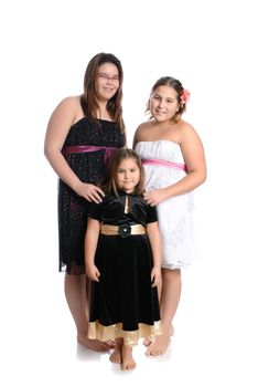 Three young girls of different ages are wearing pretty dresses and are isolated on a white background.