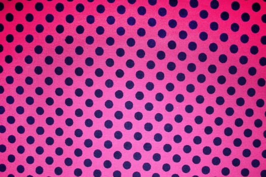 A background of a pink fabric with black dots.