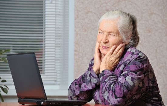 The elderly woman in front of the laptop. A photo in a room