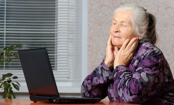 The elderly woman in front of the laptop. A photo in a room