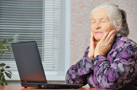 The elderly woman in front of the laptop. A photo in a room